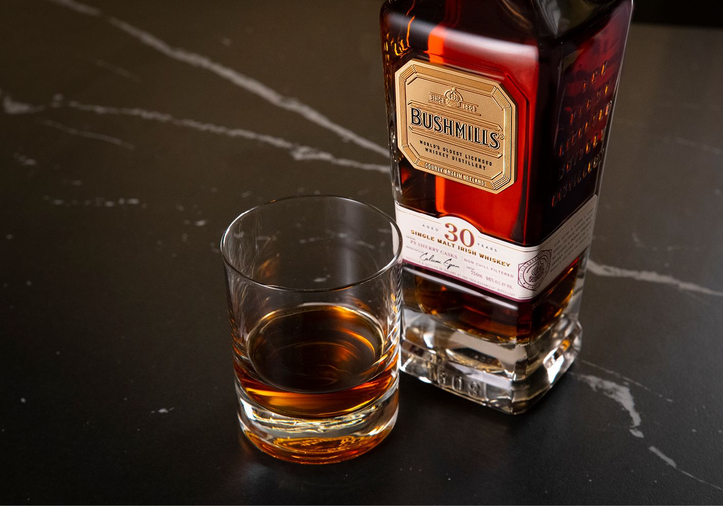 A bottle and tumbler of Bushmills 30 Year Old Single-Malt Irish Whiskey