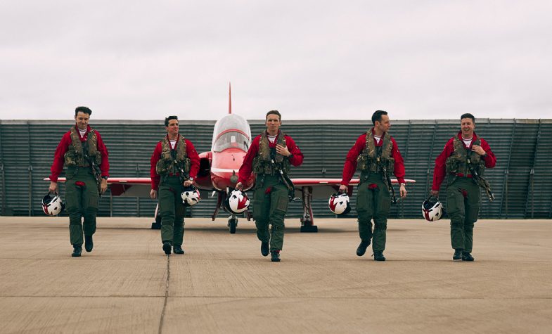 Five Red Arrows team members walking in front of a plane