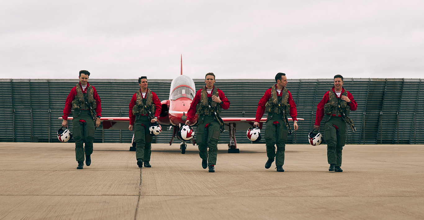 Five Red Arrows team members walking in front of a plane