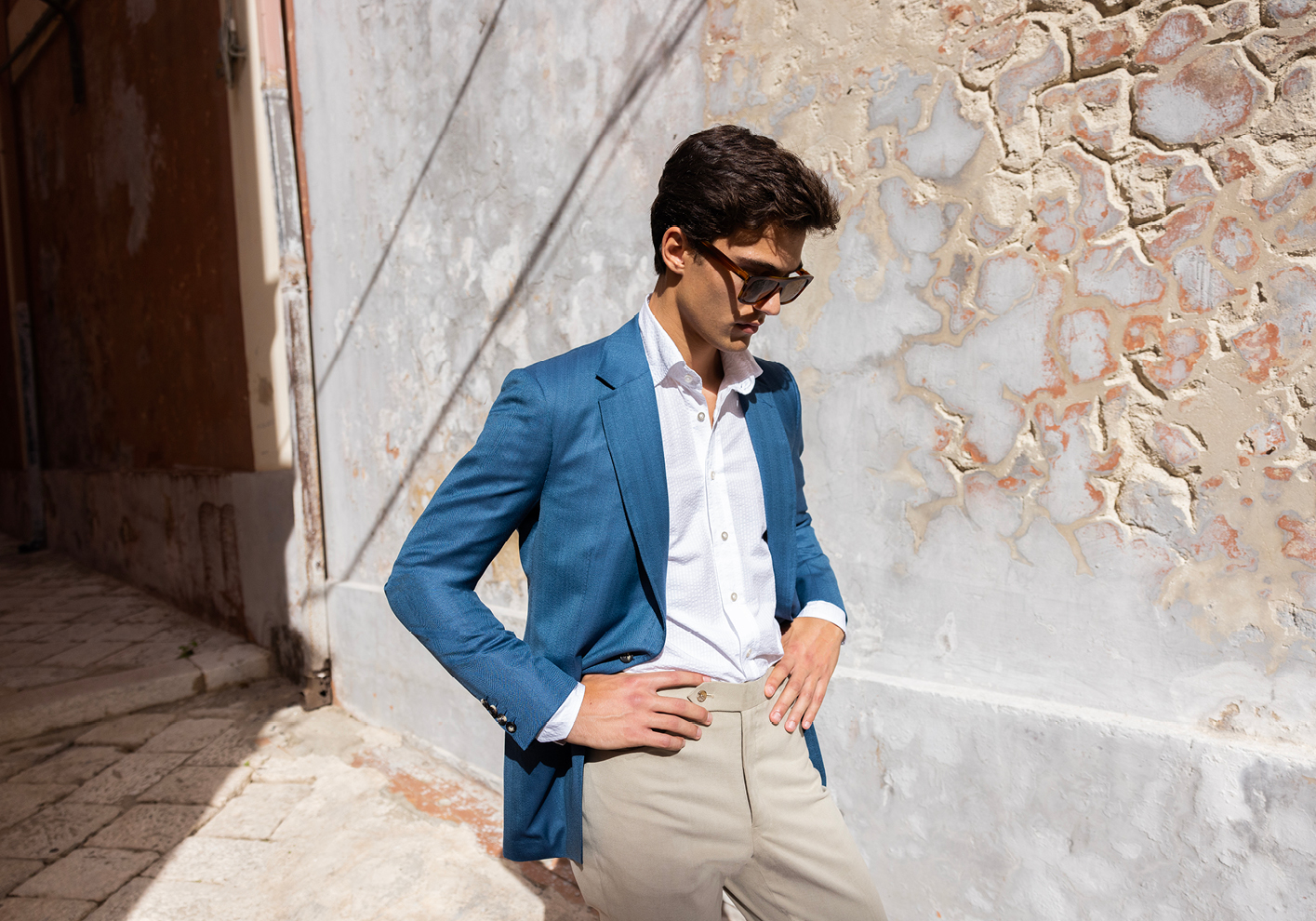 A man wearing a bespoke blue jacket and light trousers from Oliver Brown