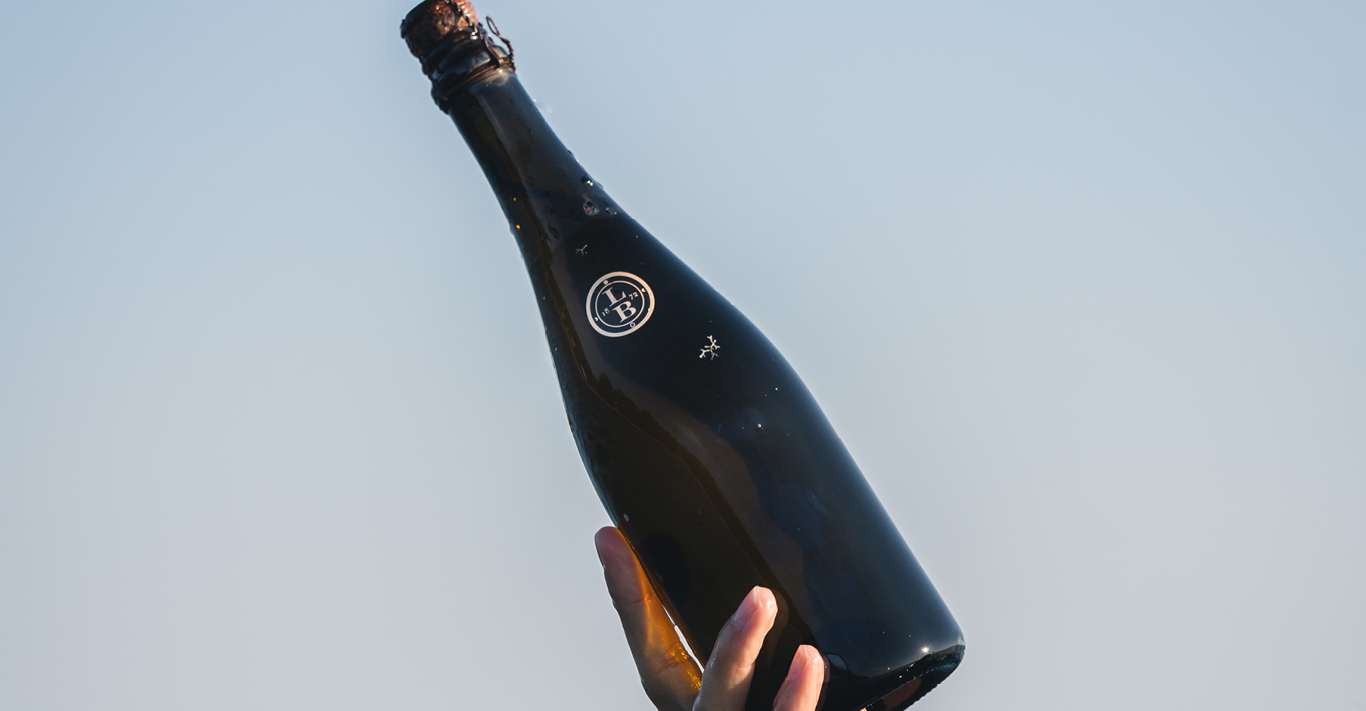 Leclerc Briant bottle held by a hand above water