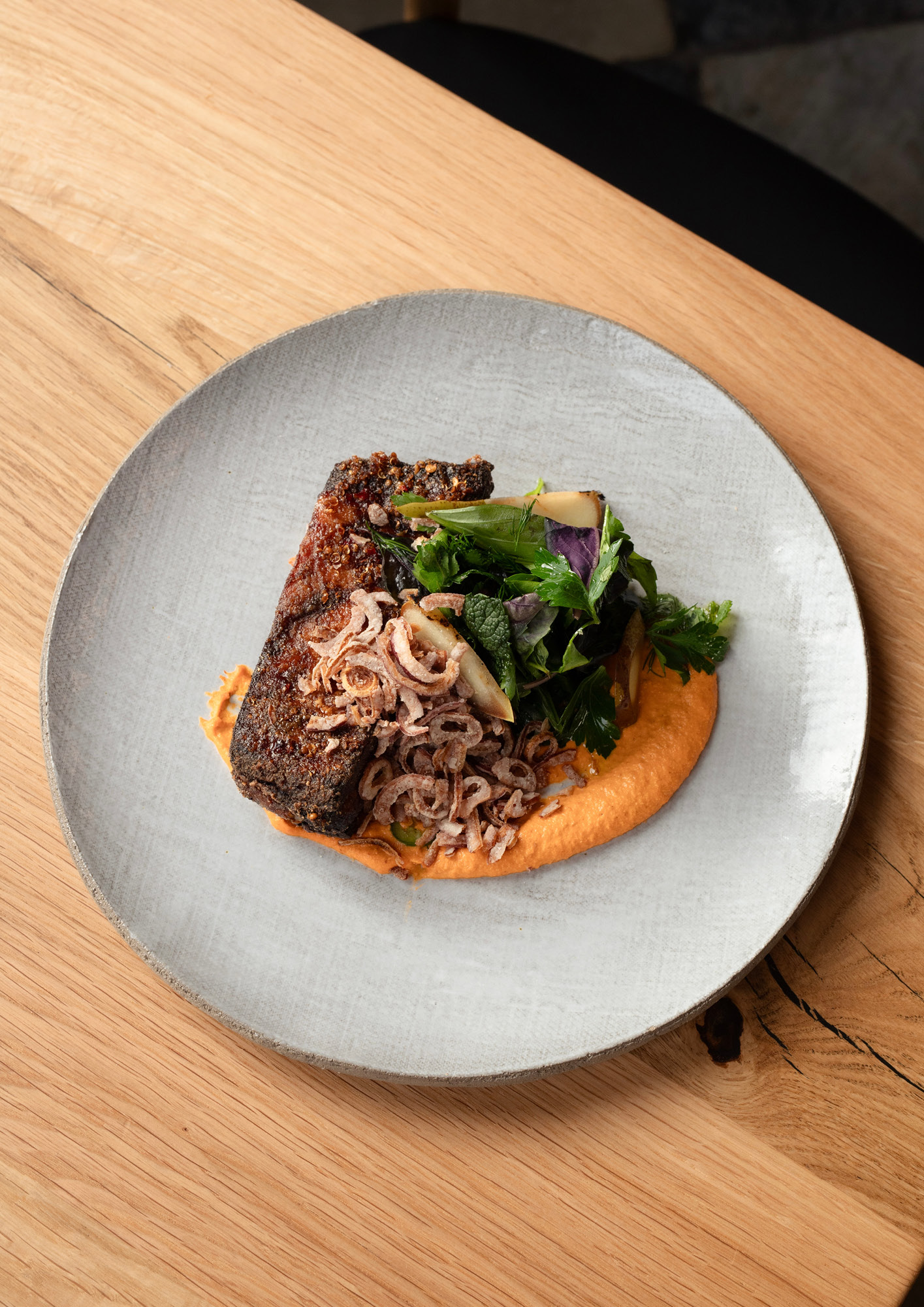 Pork rib with romesco, green leaves, crispy onions and caramel vinegar sauce